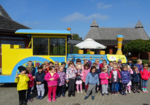 Dzieci stoją przed żółto-niebieską kolejką.